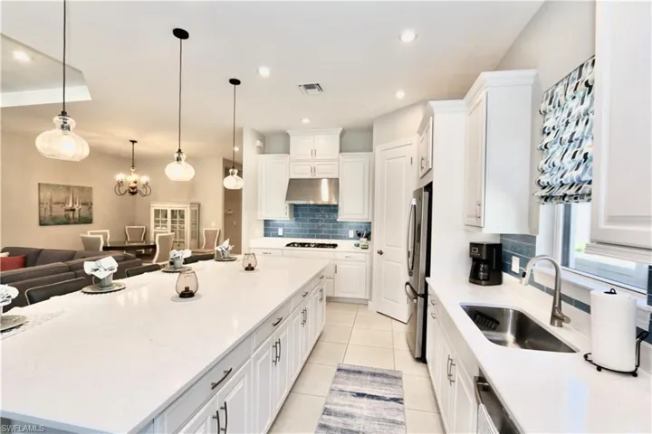 Kitchen featuring white cabinetry, hanging lights, stainless steel appliances, and open floor plan