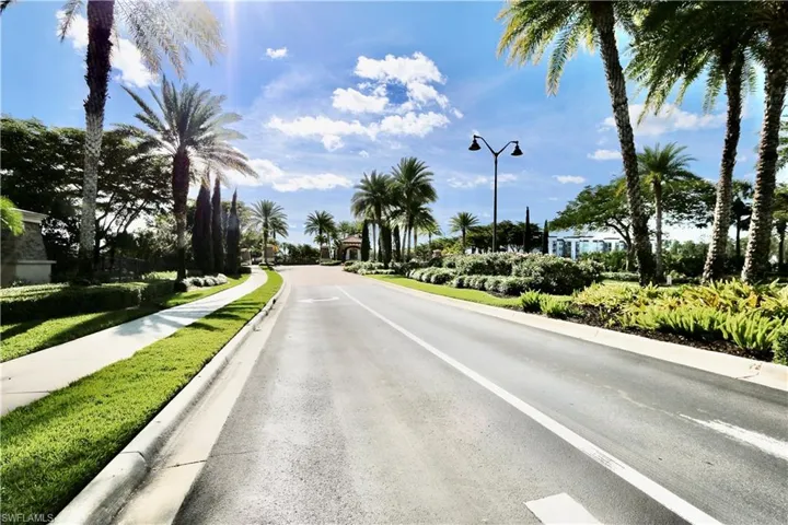 View of asphalt street featuring street lights, sidewalks, and curbs