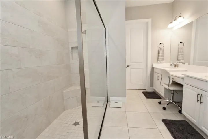 Bathroom with double vanity, a walk in shower, and light tile patterned floors