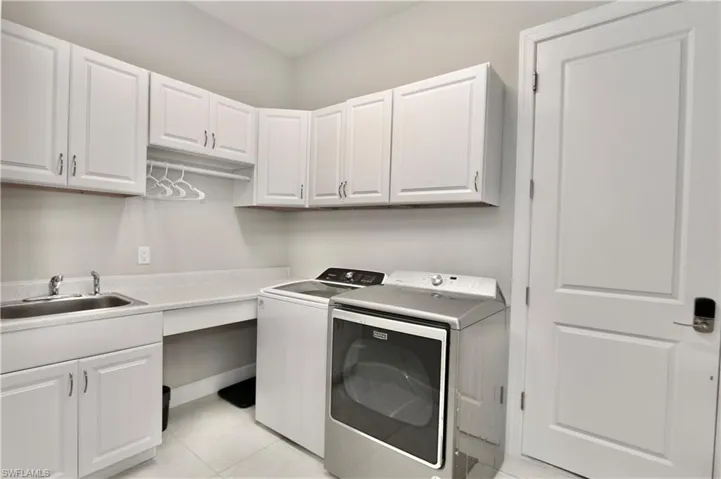 Laundry room with separate washer and dryer, light tile patterned flooring, and cabinet space