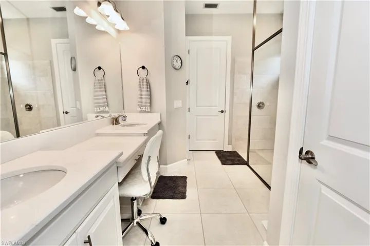Full bathroom with walk in shower, double vanity, and light tile patterned flooring