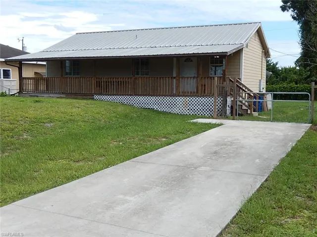 View of front of home with a front yard, covered porch, and a metal roof