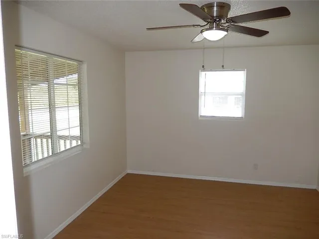 Empty room with dark wood-style floors, ceiling fan, and a textured ceiling