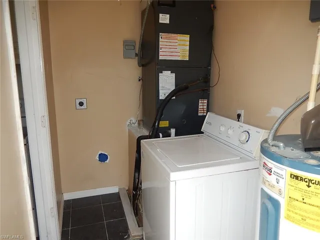 Laundry area with washer / dryer, heating unit, and dark tile patterned floors