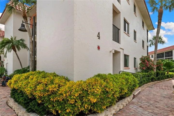 Stucco exterior with a terracotta tile roof, complemented by mature palm trees and manicured landscaping