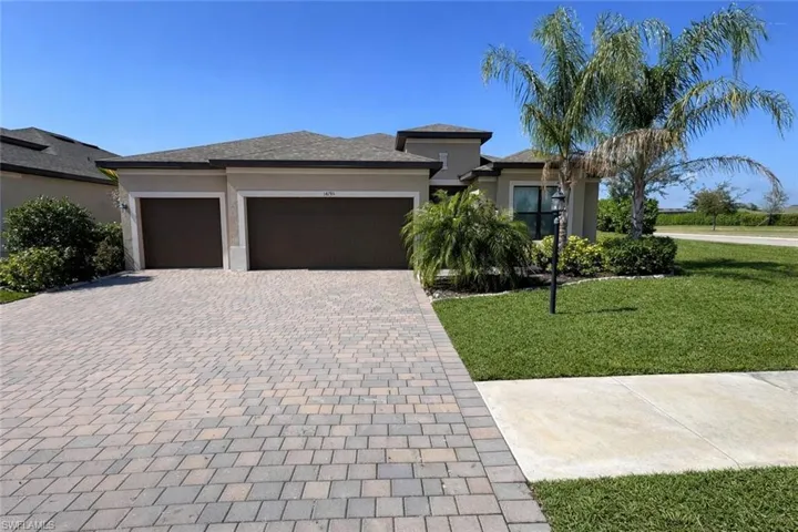 Prairie-style home featuring a front yard, driveway, stucco siding, and an attached garage