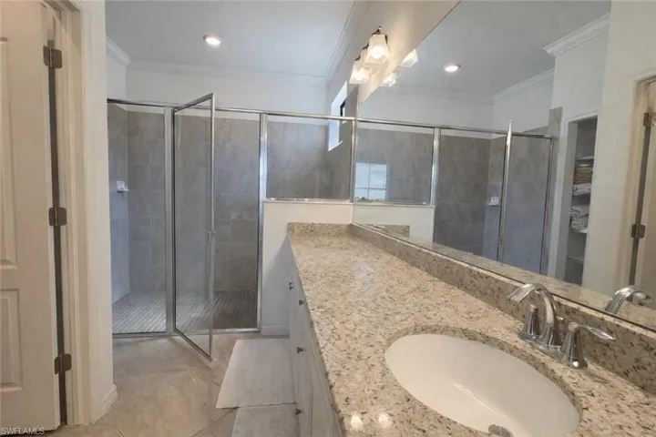 Bathroom featuring vanity, a shower stall, ornamental molding, light tile patterned floors, and recessed lighting