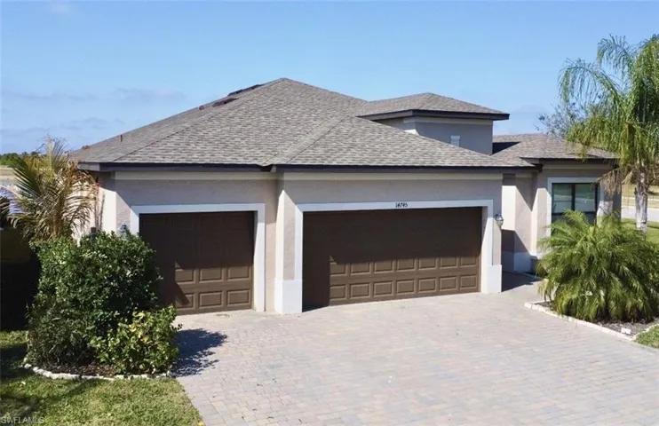 View of front of home featuring a shingled roof, stucco siding, decorative driveway, and a garage