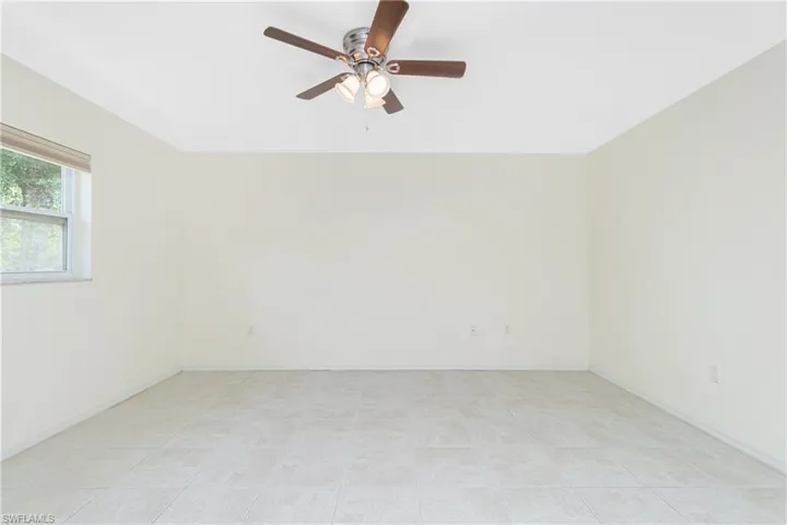 Empty room with a ceiling fan and light tile patterned flooring