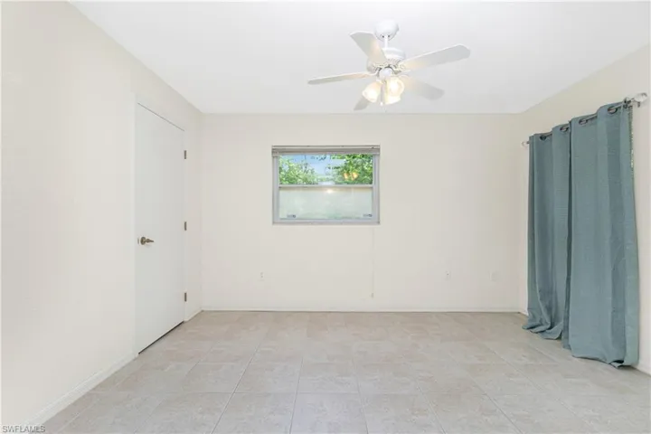 Empty room featuring ceiling fan and light tile patterned floors