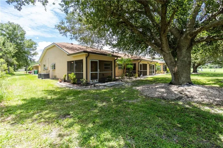 Back of property with a sunroom, stucco siding, and a lawn