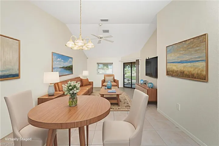 Dining space with a chandelier, high vaulted ceiling, a ceiling fan, and light tile patterned floors