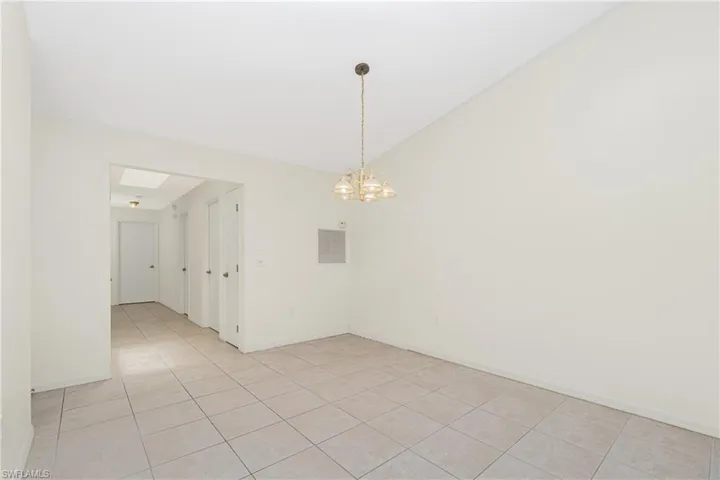 Empty room with light tile patterned floors, a chandelier, and lofted ceiling