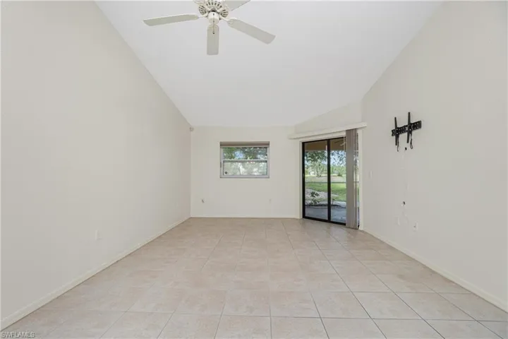 Unfurnished room featuring ceiling fan, light tile patterned floors, and lofted ceiling