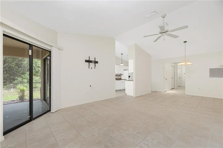 Unfurnished living room featuring ceiling fan, a chandelier, light tile patterned floors, and high vaulted ceiling