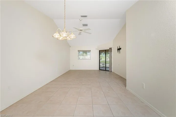 Unfurnished room featuring a chandelier, lofted ceiling, a ceiling fan, and light tile patterned flooring