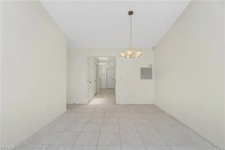 Unfurnished room with light tile patterned floors and a chandelier