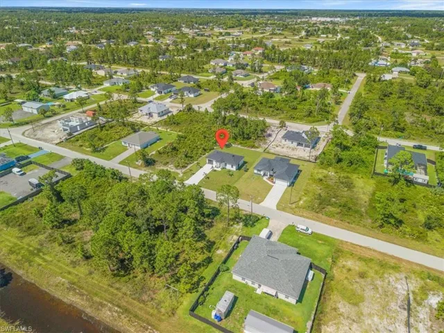 Aerial view of property and surrounding area featuring nearby suburban area and a tree filled landscape