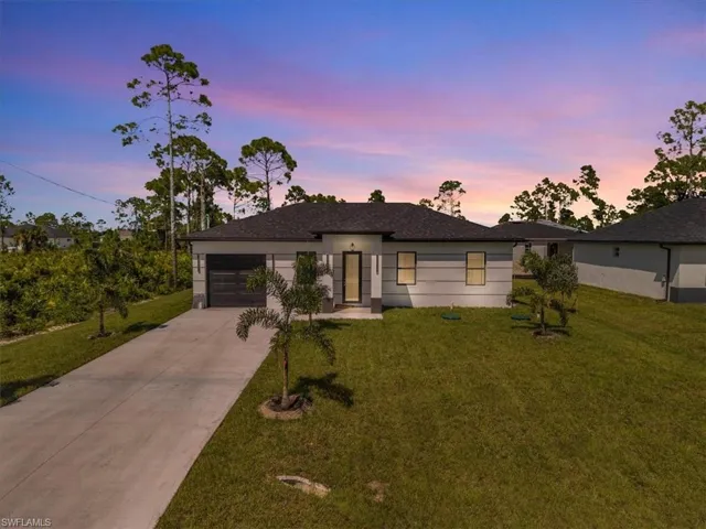 View of front facade with concrete driveway, a yard, and a garage