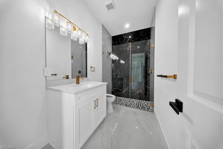 Bathroom with light marble finish floors, a marble finish shower, vanity, and recessed lighting