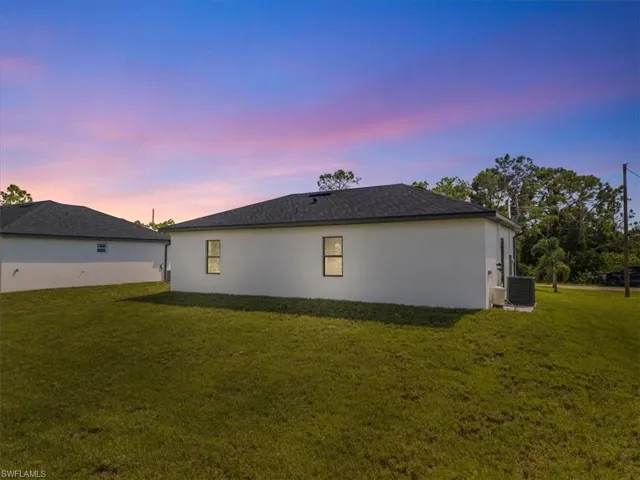 Property exterior at dusk with a yard and stucco siding