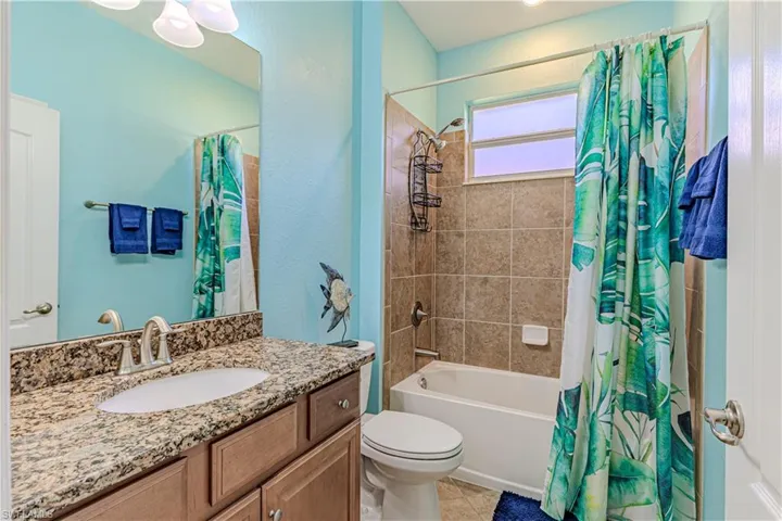 Full bathroom featuring tile patterned flooring, shower / bath combo with shower curtain, vanity, and toilet