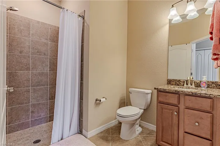 Bathroom featuring vanity, tile patterned flooring, toilet, and a shower with shower curtain