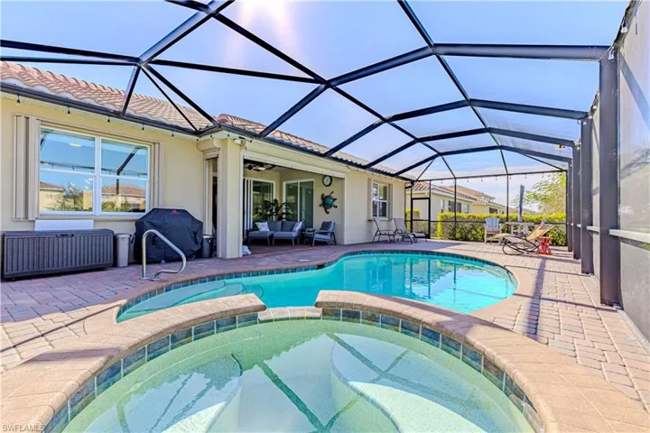 View of swimming pool with ceiling fan, an in ground hot tub, and a lanai