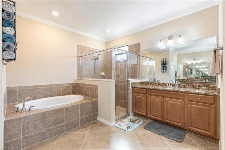 Bathroom with vanity, plus walk in shower, crown molding, and tile patterned floors