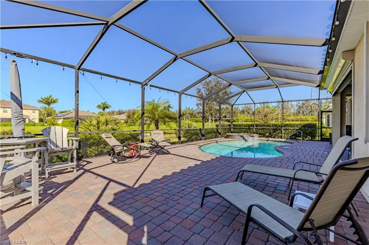 View of swimming pool with glass enclosure and a patio