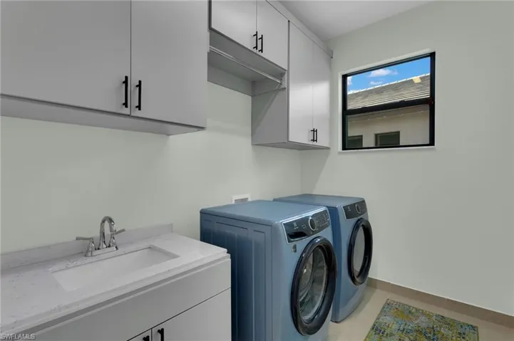 Laundry Room with upgraded washer/dryer, custom cabinets & laundry sink