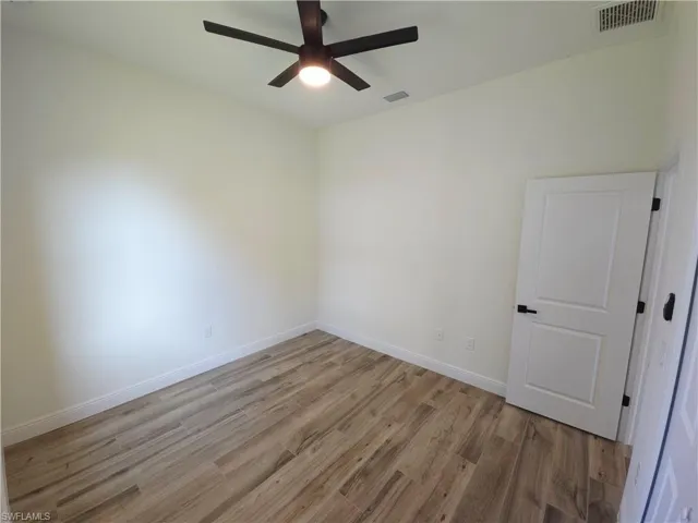 Bedroom 2, wood-finish flooring, white walls, and a modern ceiling fan with integrated lighting