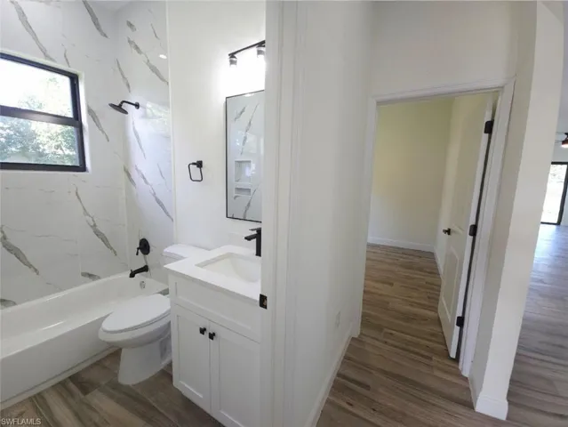 Bathroom featuring a white vanity with a rectangular sink, black fixtures, and a shower/tub combination with tiled walls