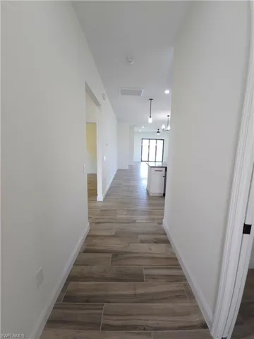 Wood-finish flooring, recessed lighting, and modern pendant fixtures