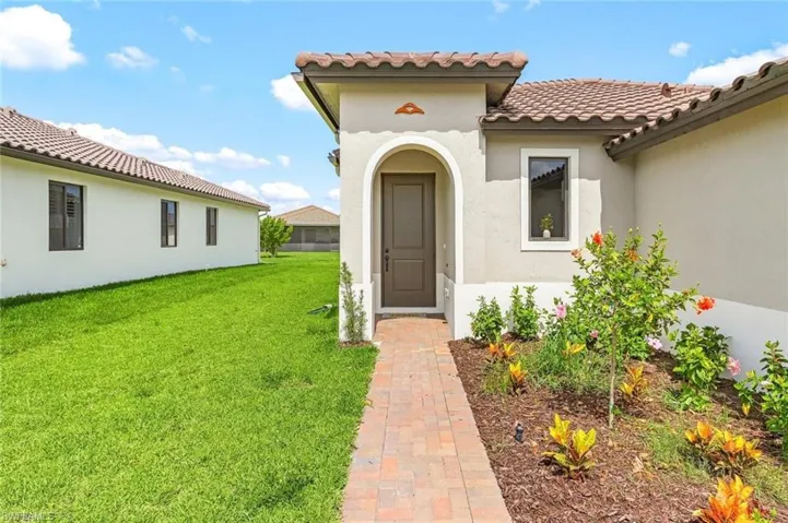 Entrance to property featuring a yard, stucco siding, and a tiled roof