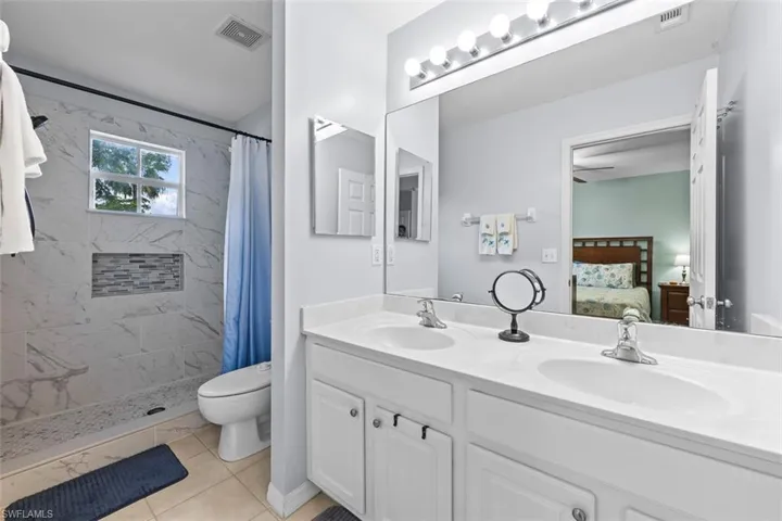 Ensuite bathroom featuring a shower stall, double vanity, and light tile patterned flooring