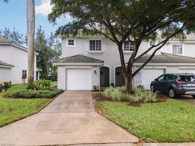 Traditional home featuring a garage, stucco siding, concrete driveway, a front lawn, and a tile roof