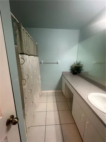 Full bath with tile patterned floors and shower / bath combo with shower curtain