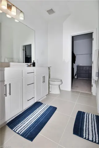 Bathroom featuring a single vanity with white cabinetry, a large wall-mounted mirror, and a three-light fixture