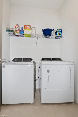 Laundry area featuring light-toned square floor tiles