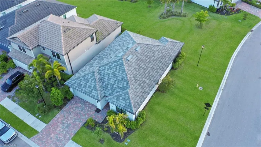 Single-story residence featuring a tile roof, light-toned exterior, and an expansive green lawn