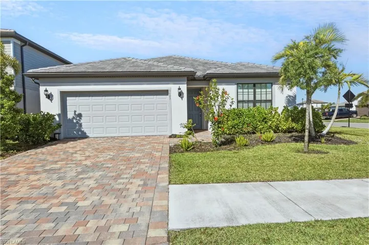 Stucco exterior home featuring a gray tiled roof and a paneled garage door