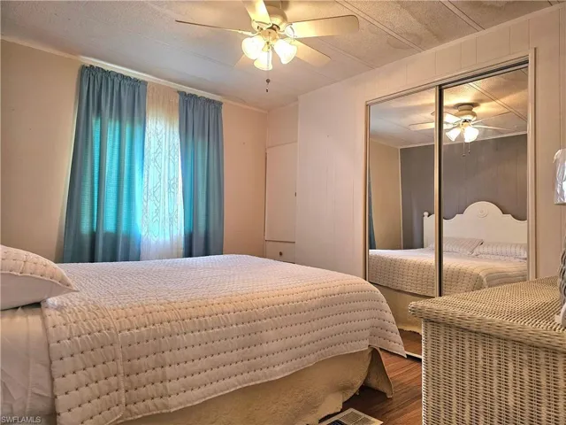 Bedroom featuring wood finished floors, a closet, wood walls, and ceiling fan