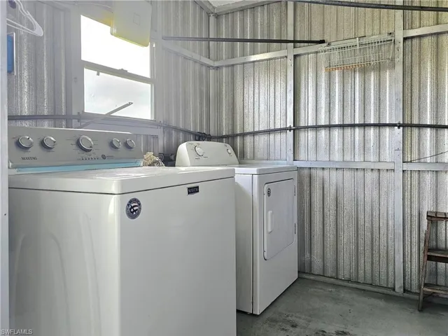 Laundry area with unfinished concrete flooring, separate washer and dryer, and metal wall