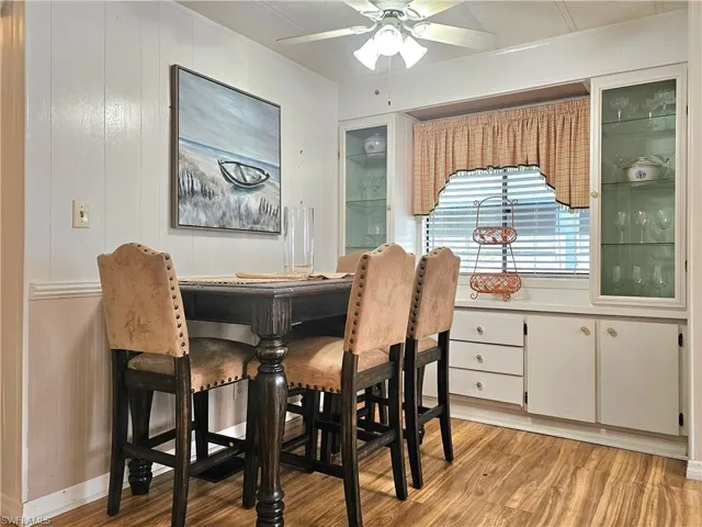 Dining area featuring crown molding, light wood-type flooring, wooden walls, and a ceiling fan