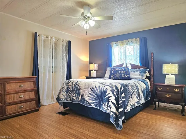 Bedroom with wood finished floors, ceiling fan, and ornamental molding