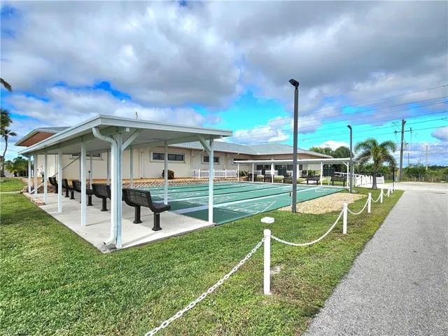 View of property's community with a lawn and shuffleboard