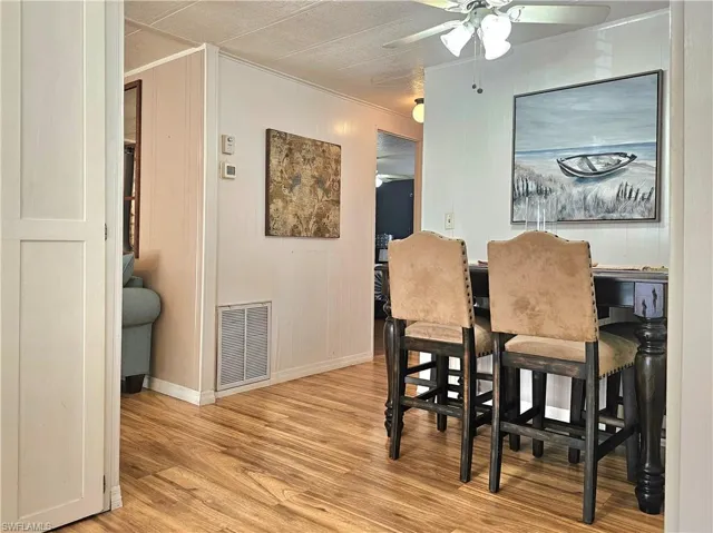 Dining room featuring crown molding, light wood-style flooring, and a ceiling fan