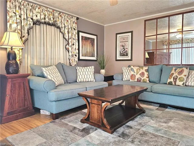 Living room with ornamental molding, a ceiling fan, and wood finished floors