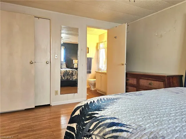 Bedroom with wood finished floors and connected bathroom